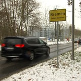 Ein Auto fährt an einem Ortsschild vorbei.