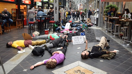 Teilnehmer der Protestaktion liegen auf dem Boden.