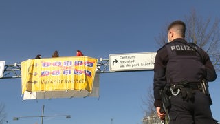 Aktivisten von Extinction Rebellion sitzen auf einer Schilderbrücke