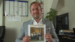 Fabian Siemering hält ein Bild in den Händen. Es zeigt seine Schulklasse, die an der Pisa-Studie teilgenommen hatte.