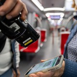Ein Fahrkartenkontrolleur kontrolliert mit einem elektronischen Lesegerät in der U-Bahn Gäste.