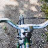 Ein Fahrradlenker und ein Reifen aus Sicht des Fahrers.
