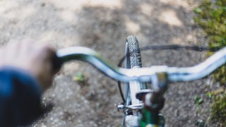 Ein Fahrradlenker und ein Reifen aus Sicht des Fahrers.