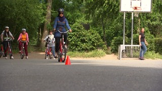 Geflüchtete Frauen lernen Fahrrad fahren in einem Fahrradkurs. 