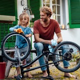 Vater und Tochter beim Fahrradputzen.