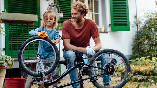 Vater und Tochter beim Fahrradputzen.