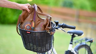 Hand greift Tasche aus Fahrradkorb