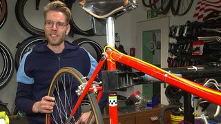 Fahrradhändler Sebastian bei der Reparatur eines Fahrrads in seiner Werkstatt.