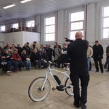 Ein Mann mit einem Fahrrad steht vor einer größeren Gruppe Menschen.