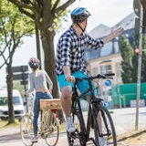 Ein Fahrradfahrer schaut nach hinten zu einer anderen Radfahrerin und macht eine Beschwerdegeste.