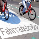 Zwei Fahrräder fahren über eine Straße mit dem Aufdruck "Fahrradstraße".