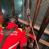 Ein angeseilter Feuerwehrmensch in einem Fahrstuhlschacht