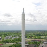 Der Bremer Fallturm sieht aus wie ein überdimensionaler Bleistift, der in den Himmel ragt. Im Hintergrund ist das Uni-Gelände zu sehen.