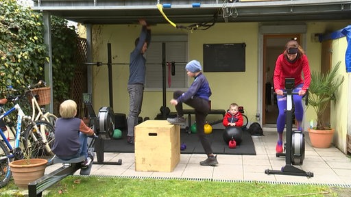 Eine Familie macht zusammen draußen im Garten Sport in ihrem eigenen kleinem Fitnessstudio.