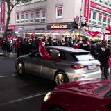Türkei-Fans schwenken Fahen aus Autos und auf dem Gehweg.