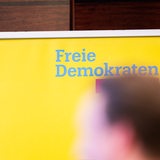 Ein unscharfer Kopf vor einem FDP-Logo (Symbolbild)