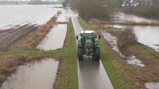 Ein Traktor zwischen überschwemmten Feldern.