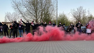 Fans der Fischtown Pinguins feiern mit FFP2-Masken in einer roten Rauchwolke ihre Mannschaft nach dem knappen-Playoff-Aus.