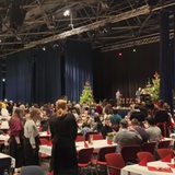 In einer Halle sitzen zahlreiche Personen an Tischen.