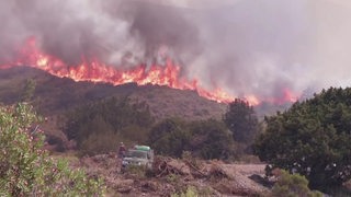 Ein großes Feuer zieht sich an einem Bergkamm entlang.
