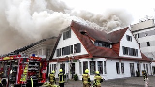 Dichter Rauch steigt aus dem Dach eines brennenden Hauses auf.