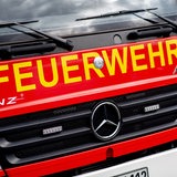 Ein Einsatzfahrzeug der Feuerwehr steht im Rahmen einer Übung auf einem Parkplatz.
