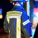Ein Feuerwehrmann steht in Uniform an einem Einsatzort.