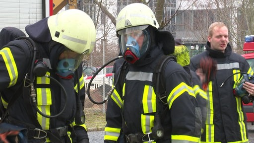Mehrere Feuerwehrmänner sind in ihren Schutzausrüstungen zu sehen.