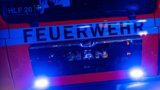 Ein Feuerwehrauto ist mit Blaulicht auf dem Weg zum Einsatz.