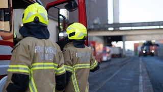 Feuerwehrmänner in Einsatzkleidung an einem Einsatzwagen