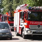 Mehrere Feuerwehrwagen fahren eine Straße entlang.
