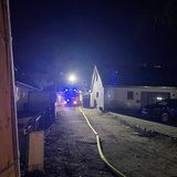 Neben einem Haus in Bremen-Horn steht ein Feuerwehr-Auto mit eingeschaltetem Blaulicht in der Einfahrt.