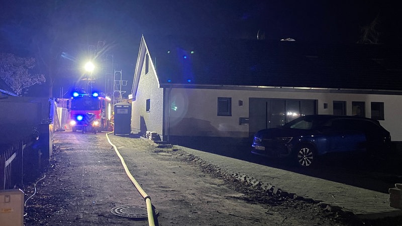 Neben einem Haus in Bremen-Horn steht ein Feuerwehr-Auto mit eingeschaltetem Blaulicht in der Einfahrt.