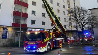Ein Feuerwehrwagen steht vor einem Hochhaus.