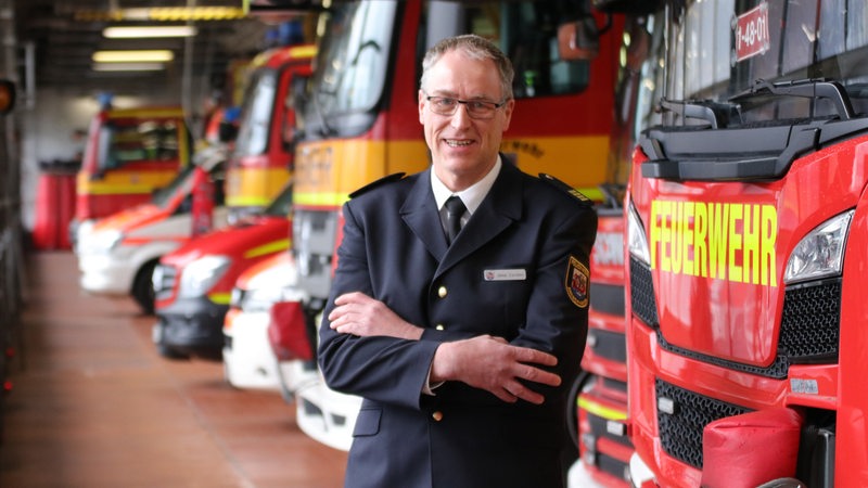 Der Leiter der Feuerwehr Bremerhaven, Jens Cordes, steht vor roten Feuerwehrwagen
