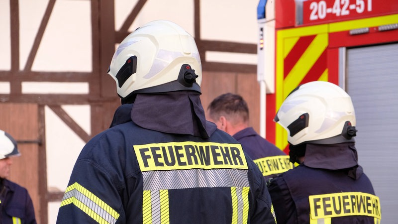 Mehrere Feuerwehrleute stehen vor einem Fachwerkhaus.