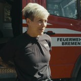 Eine Feuerwehrfrau steht vor einem Feuerwehrwagen