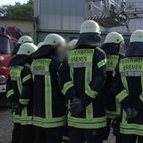 Eine Gruppe Feuerwehrmänner, die mit dem Rücken zur Kamera stehen.