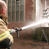 Ein Feuerwehrmann spritz die Stadtmusikanten sauber.