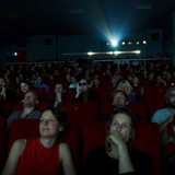 Menschen sitzen in einem dunklen Kinosaal