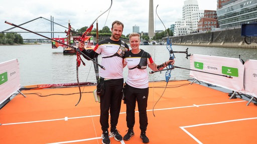 Bogenschütze Florian Unruh steht neben seiner Teamkollegin auf dem Ponton auf dem Rhein während des Finals-Wettbewerbs.