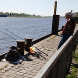 Mann steht mit Angel an der Weser