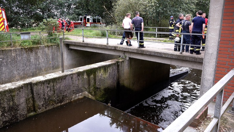 Auf dem Südarm der Wümme zwischen Fischerhude und Ottersberg stehen mehrere Feuerwehrmänner vor einem Geländer beisammen.