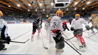 Menschen in Eishockey-Trikots trainieren auf einem Eishockey-Feld