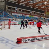 Kinder spielen Eishockey in einer Eishalle.