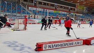 Kinder spielen Eishockey in einer Eishalle.