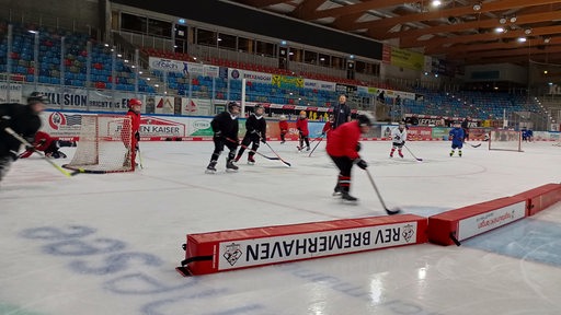 Kinder spielen Eishockey in einer Eishalle.