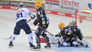 Zwei Spieler der Fischtown Pinguins am Boden, einer auf den Beinen, daneben ein Spieler des EHC München