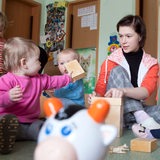 Eine junge Frau betreut Kinder in einer Kinderkrippe