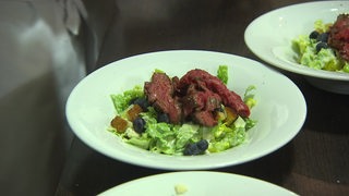 Ein Teller mit Salat drauf und Fleischstücken oben drauf.